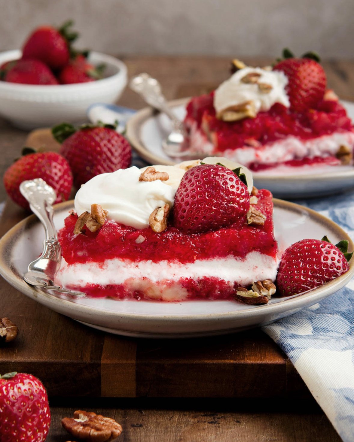 A slice of layered strawberry jello salad with a creamy sour cream center.