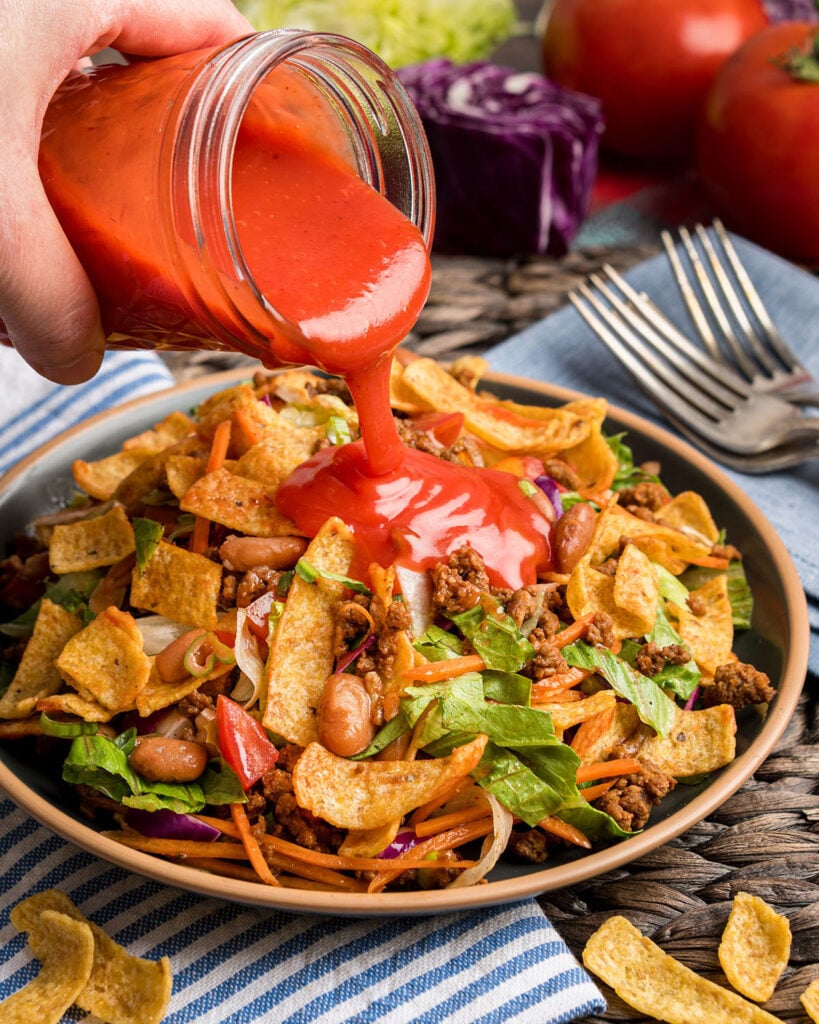 Pouring homemade Catalina dressing over this frito taco salad.