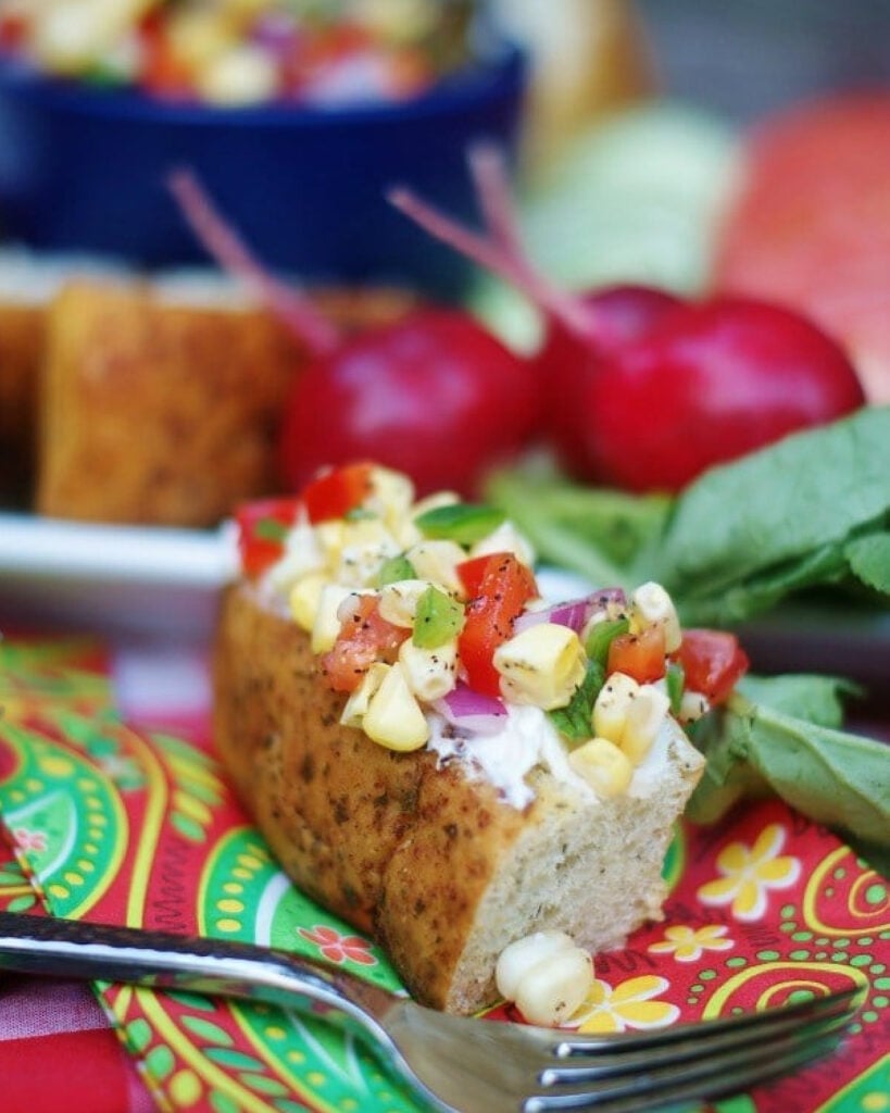 Corn relish served as a condiment atop of cream cheese spread on multi grain bread as an appetizer idea.