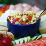 Marinated corn salad in a blue bowl on a crudite platter.