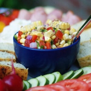 Marinated corn salad in a blue bowl on a crudite platter.