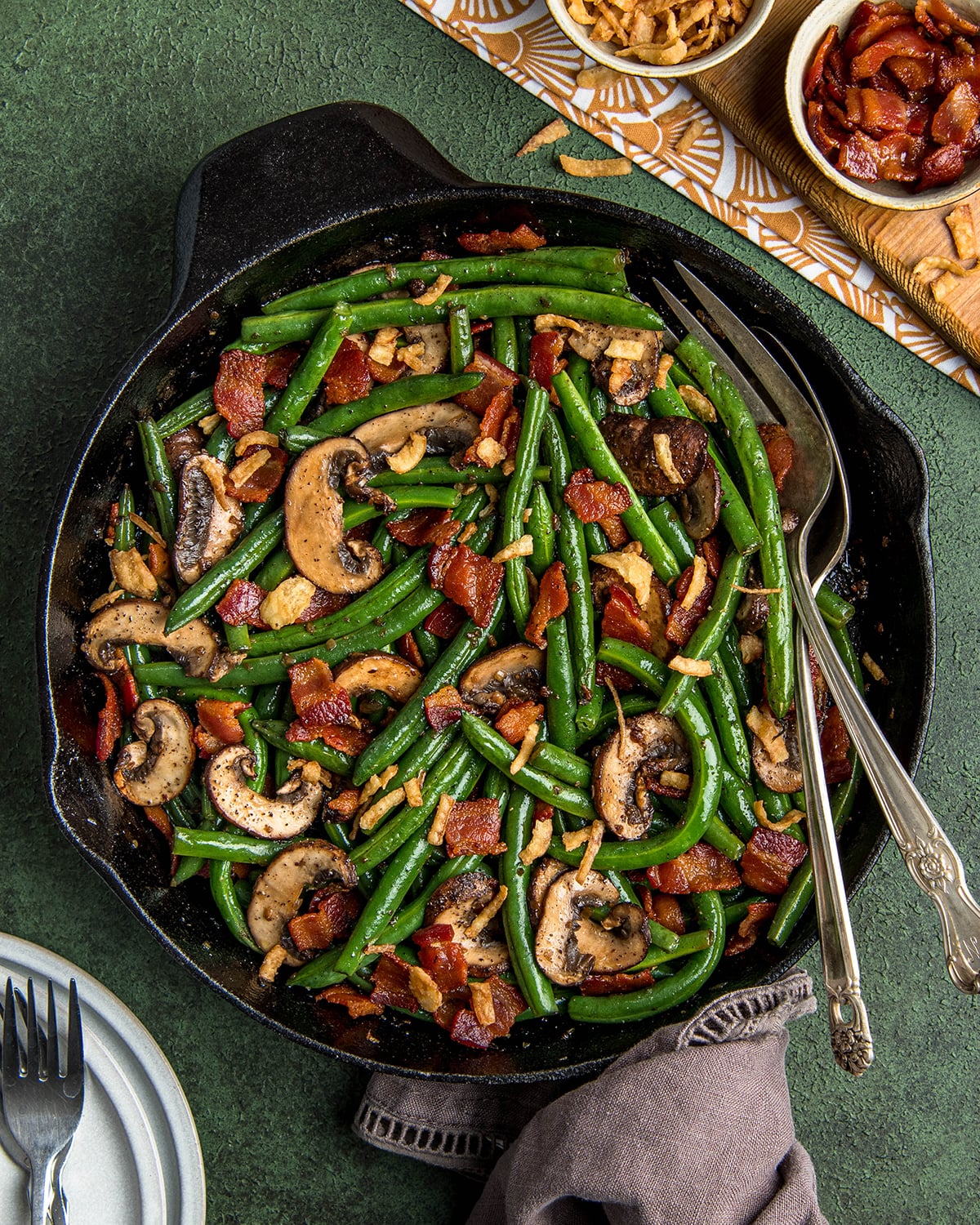 Sauteed green beans with bacon and baby portobello mushrooms in a cast iron skillet and topped with crispy french onions.