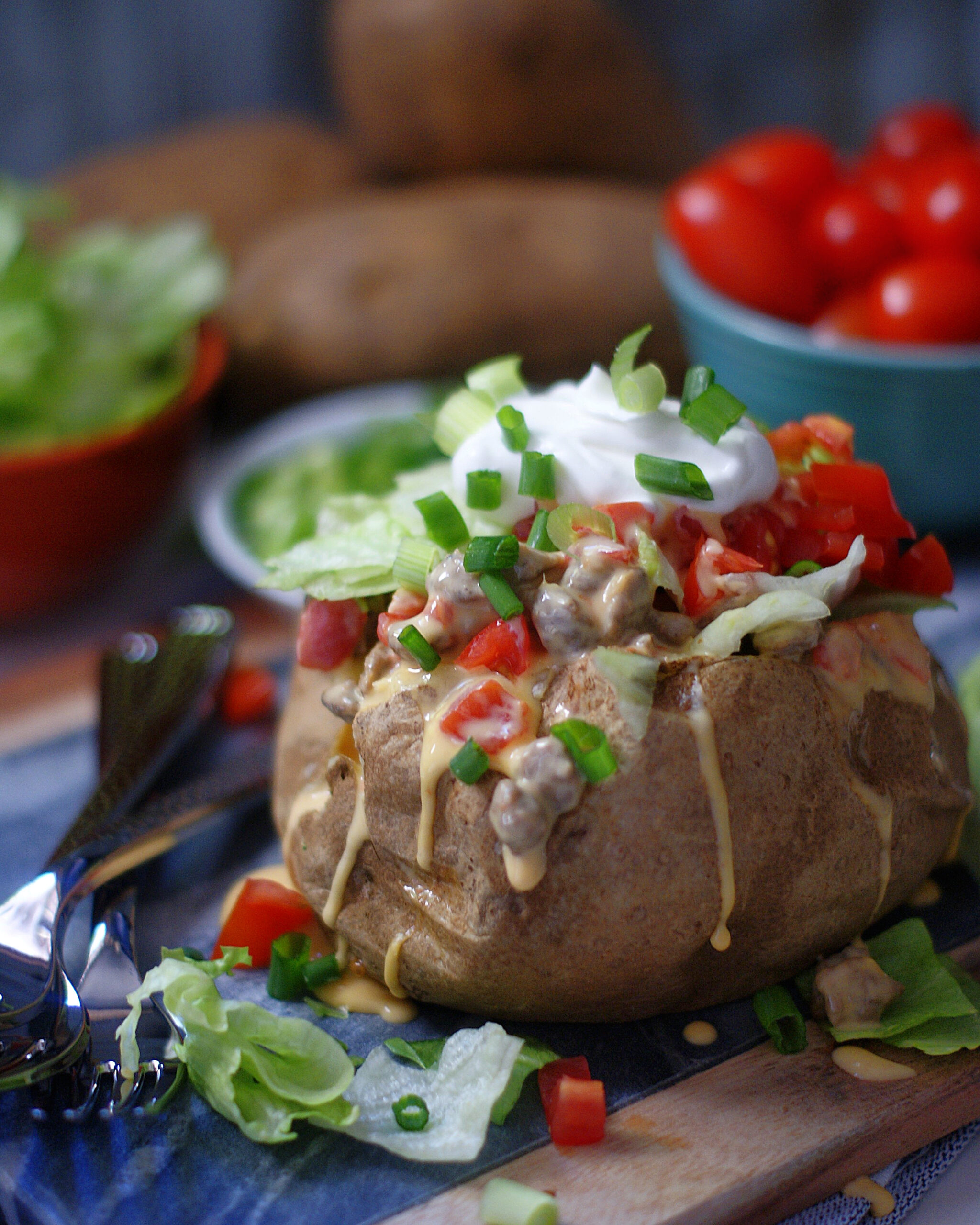 A baked potato stuffed with spicy sausage queso, lettuce, tomatoes and sour cream.
