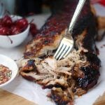A pork tenderloin being shredded with a fork.