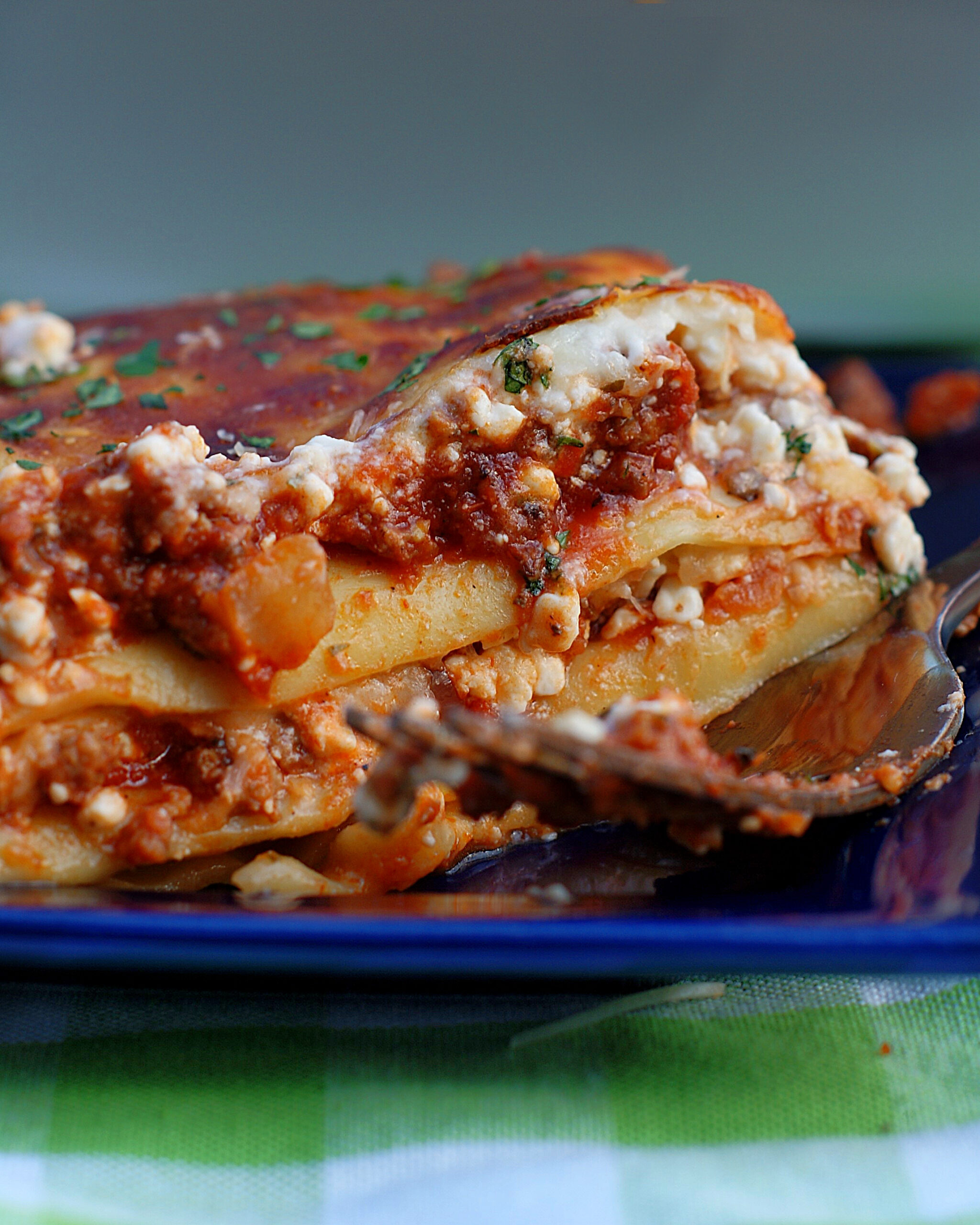 A slice of lasagna on a blue plate.