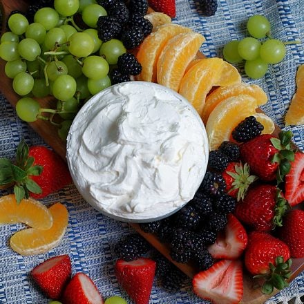 An overhead of a full bowl of marshmallow fruit dip with lots of fruit all around.