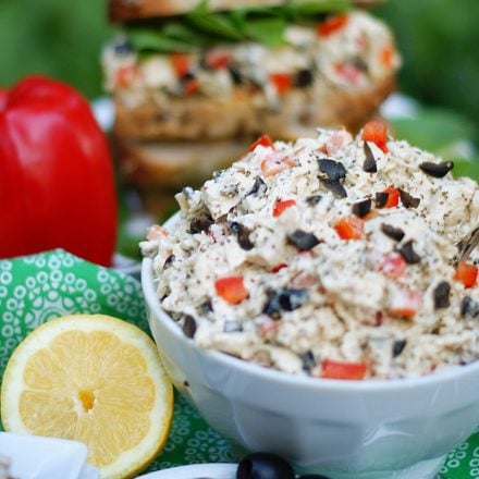 A bowl of lemon chicken salad with a chicken salad sandwich in the background.