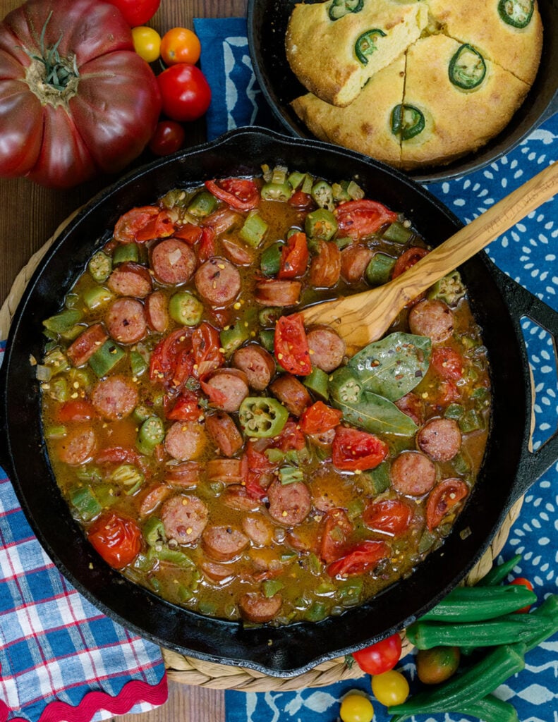 Smothered okra and tomatoes in a cast iron skillet showing how this recipe looks when it's ready on the stove top.