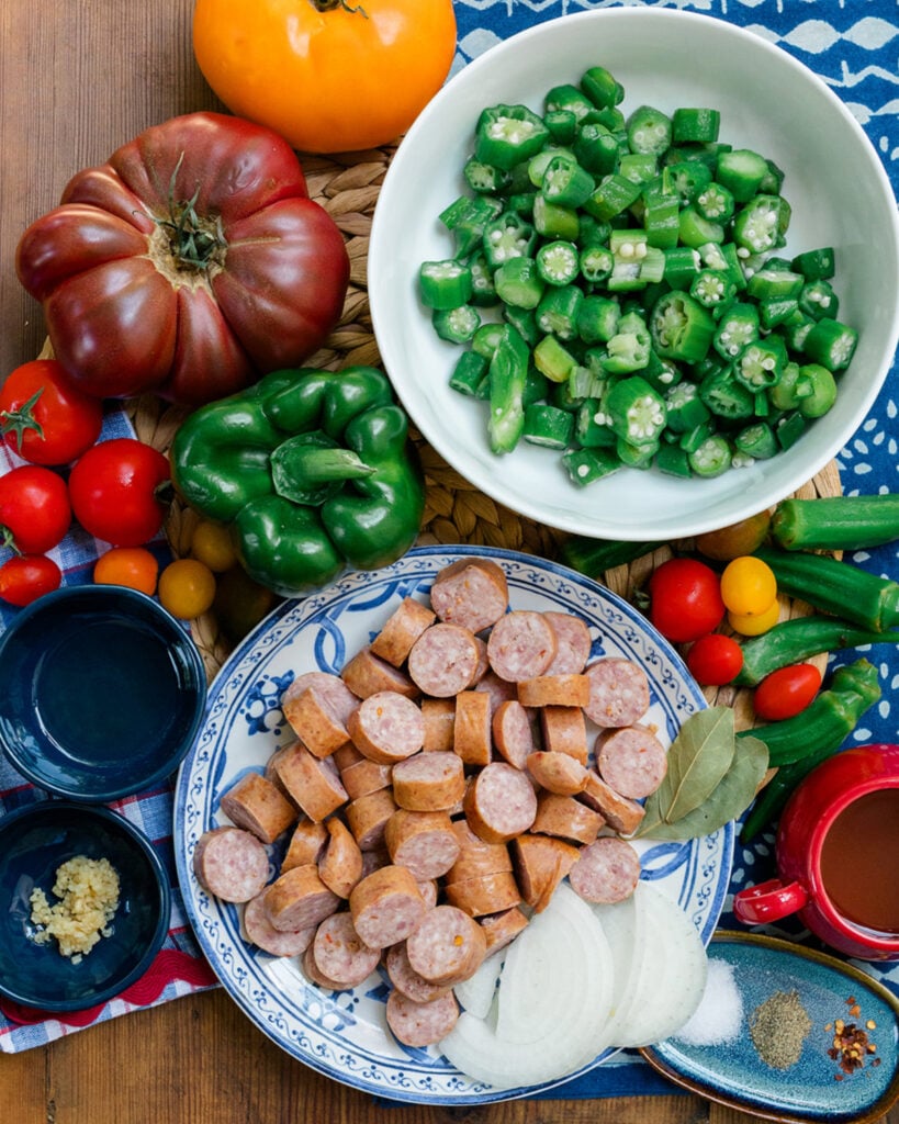 Simple ingredients used to make okra and tomatoes arranged to be easily recognized and support the written ingredient list.
