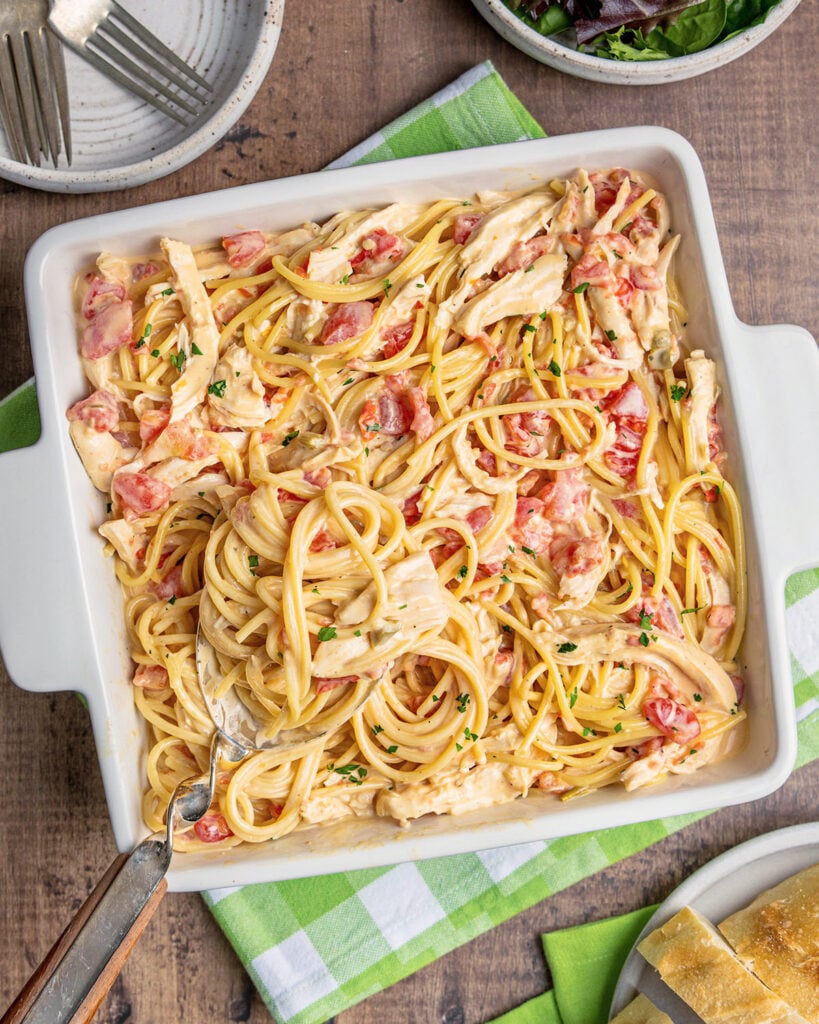 A square casserole dish fulled of spaghetti, white chicken meat, cheese and Rotel tomatoes