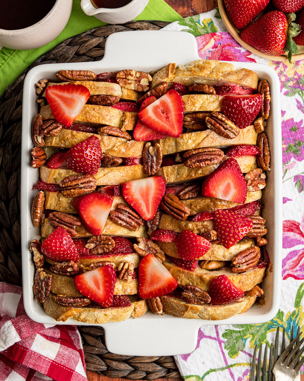 Looking down on Strawberry French Toast Casserole with slices of French bread, strawberries and halved pecans in a white casserole dish.