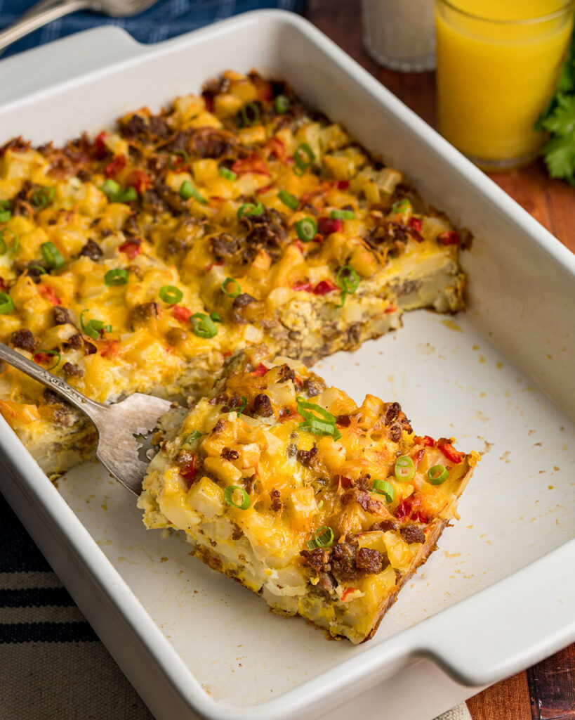 Slices of this hash brown casserole with sauage and egg being served to show how it can be sliced and put on plates for eating.