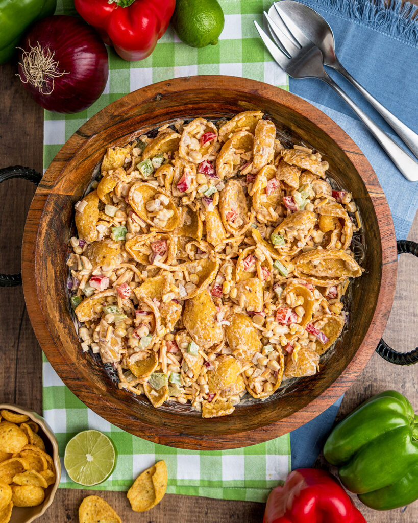 Looking down into Frito Corn Salad in a wooden bowl to show the ingredients and crunchy texture of the salad.