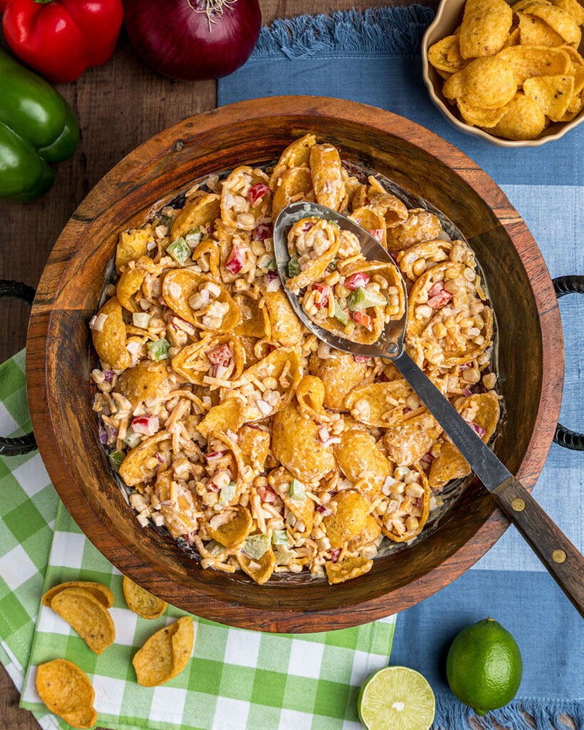 A bowl of Frito Corn Salad with a scoop in a serving spoon to show what the salad looks like with the corn chips when served.