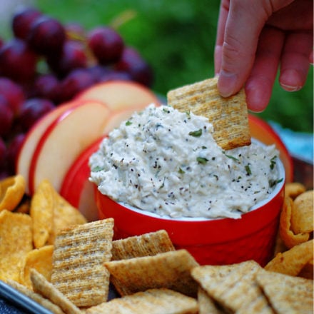 Dipping Creamy Peppercorn Parmesan Cheese Dip with a cracker