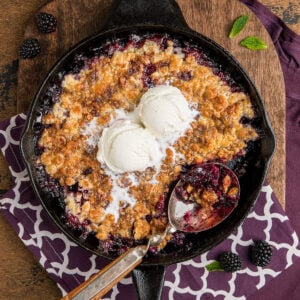 Easy southern blackberry cobbler made in a skillet with two scoops of vanilla ice cream in the center for inspiration as a serving idea.