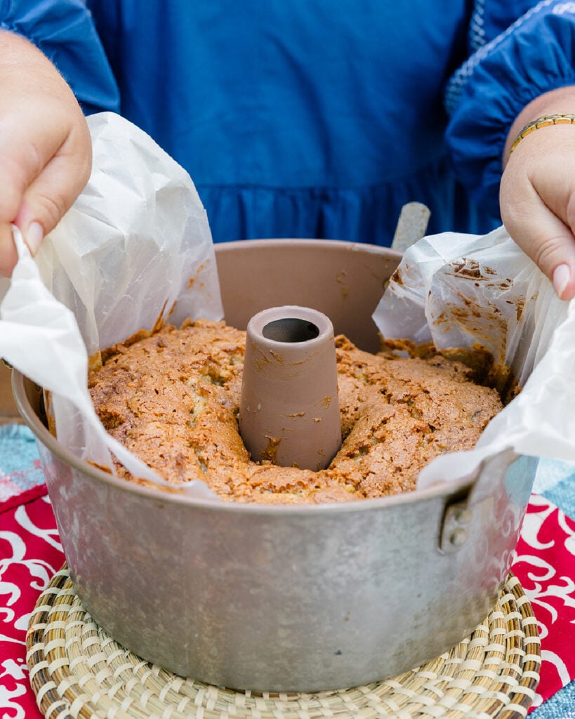 Using the wax paper lining to lift the cake from the pan to ensure no breaking or sticking.