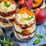 An individual trifle dessert in a cup made with fresh, sliced peaches, vanilla cream and toasted pound cake.
