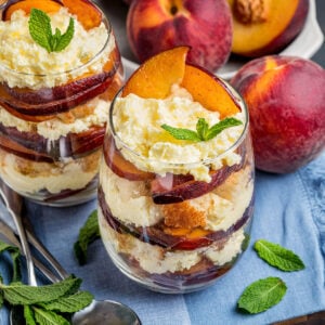 An individual trifle dessert in a cup made with fresh, sliced peaches, vanilla cream and toasted pound cake.