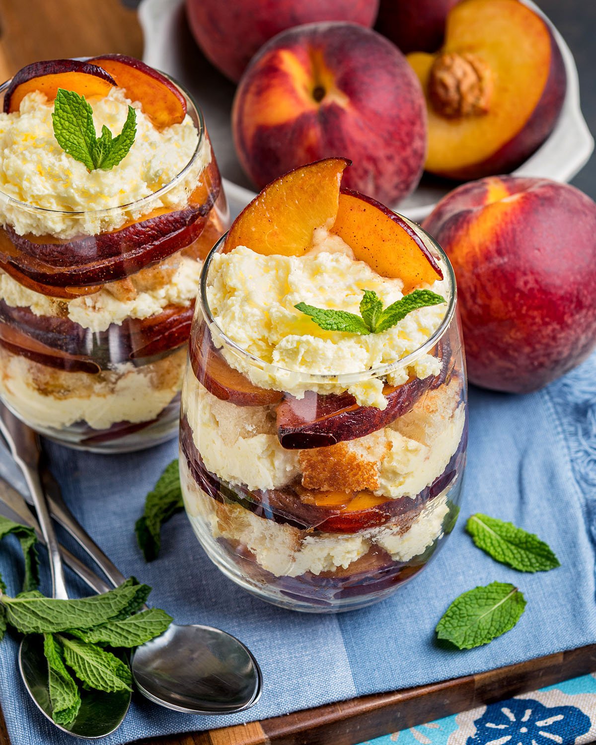 An individual trifle dessert in a cup made with fresh, sliced peaches, vanilla cream and toasted pound cake.