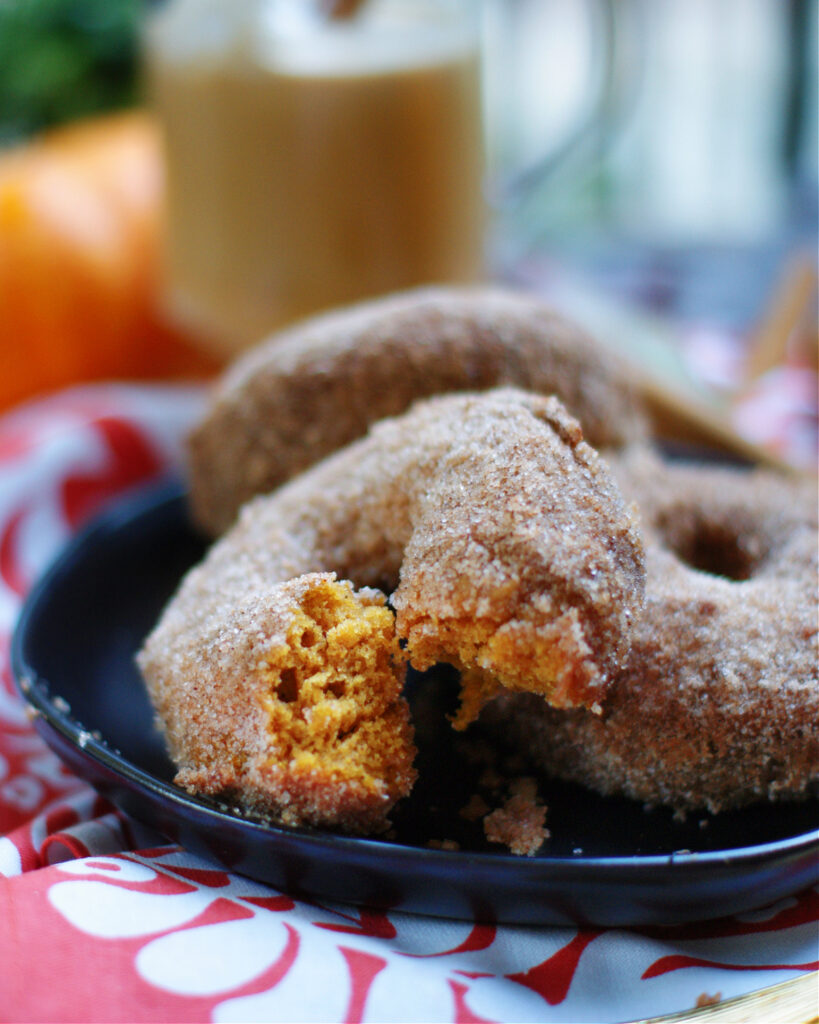 An up close photo of the soft, bright orange texture of the inside of a baked pumpkin donut.