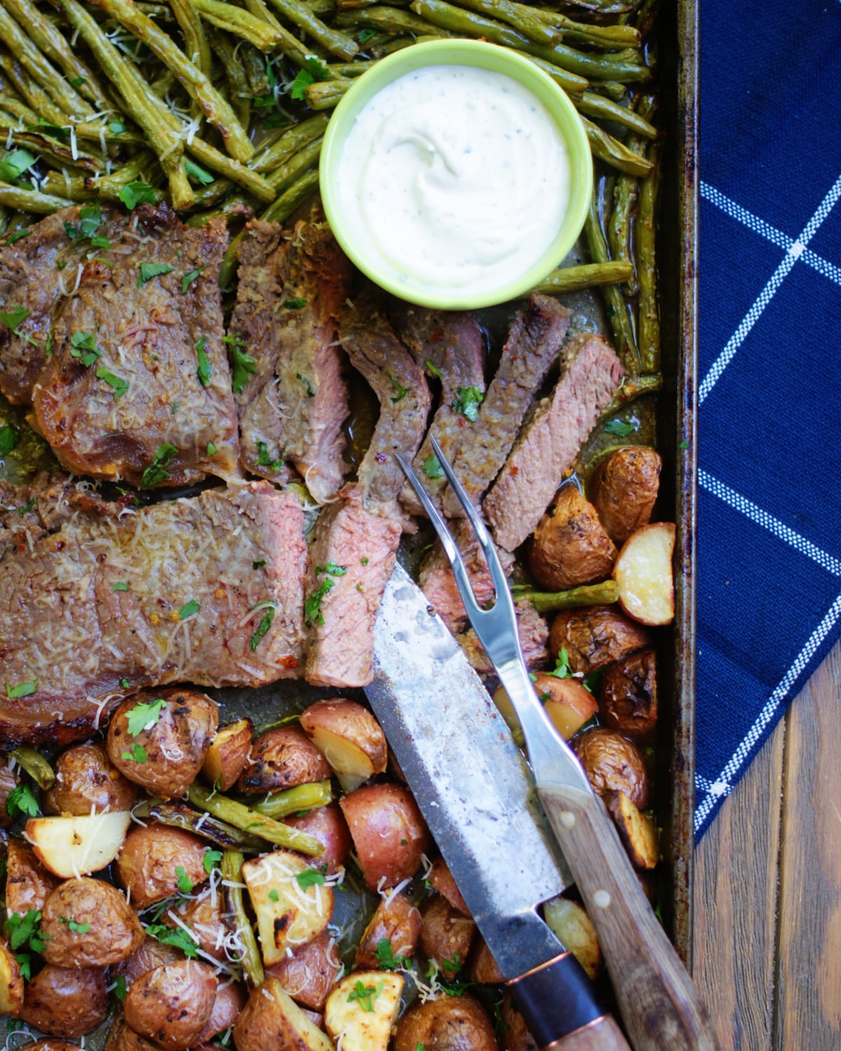 A close up of steak, potatoes, green beans cooked together on a sheet pan to show texture of the raosted vegetables and steak and the seasonings.