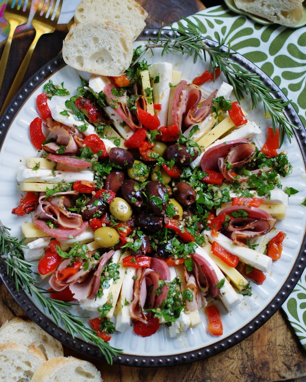 A ring of marinated cheese slices with ham and salami filled with marinated olives in the middle to create a muffuletta style appetizer for parties.