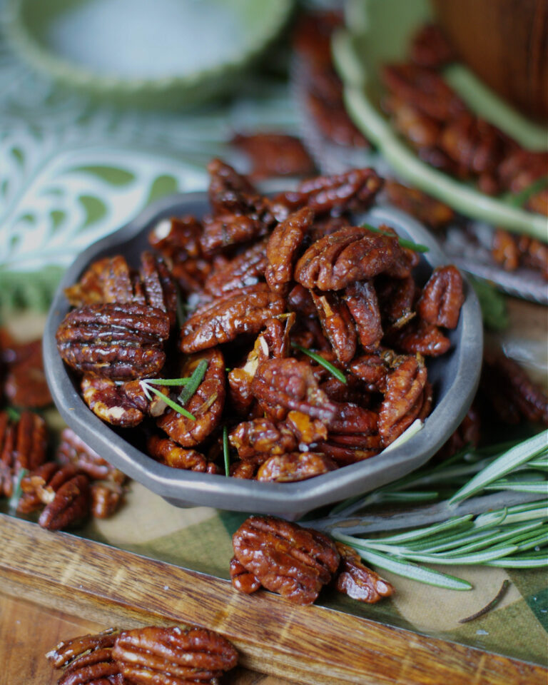 Rosemary Pecans in a pewter bowl with fresh rosemary and green cocktail napkins as a party appetizer idea.