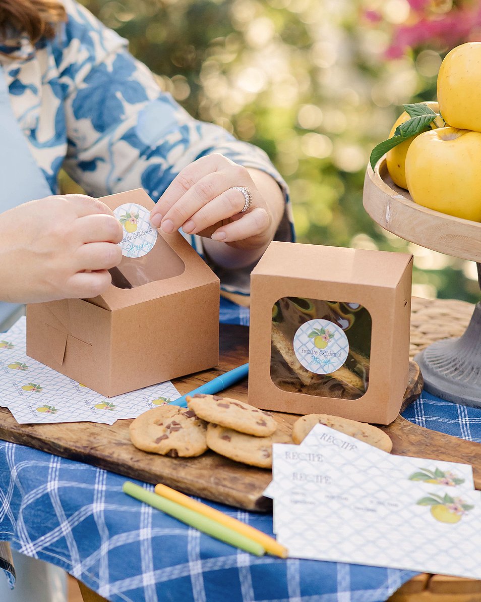 Adding "from the kitchen of" gift sticker to a bakery box of cookies.