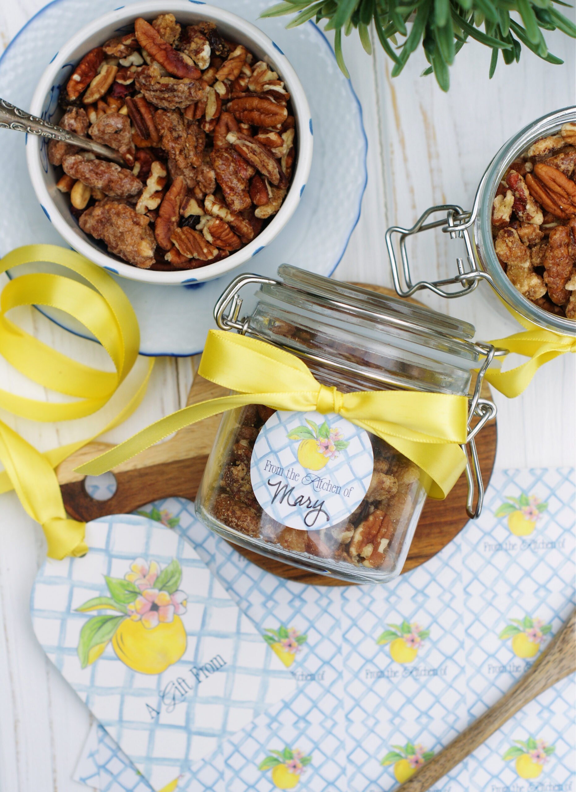 A jar of pecans with the custom Southern Discourse "from the kitchen of" gift sticker and a yellow ribbon.