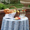 A snack table set with cheese, bread, fruit and drinks and a linen tea towel lining the basket.