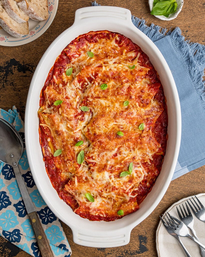 A baking dish filled with stuffed cheese manicotti and topped with marinara sauce.
