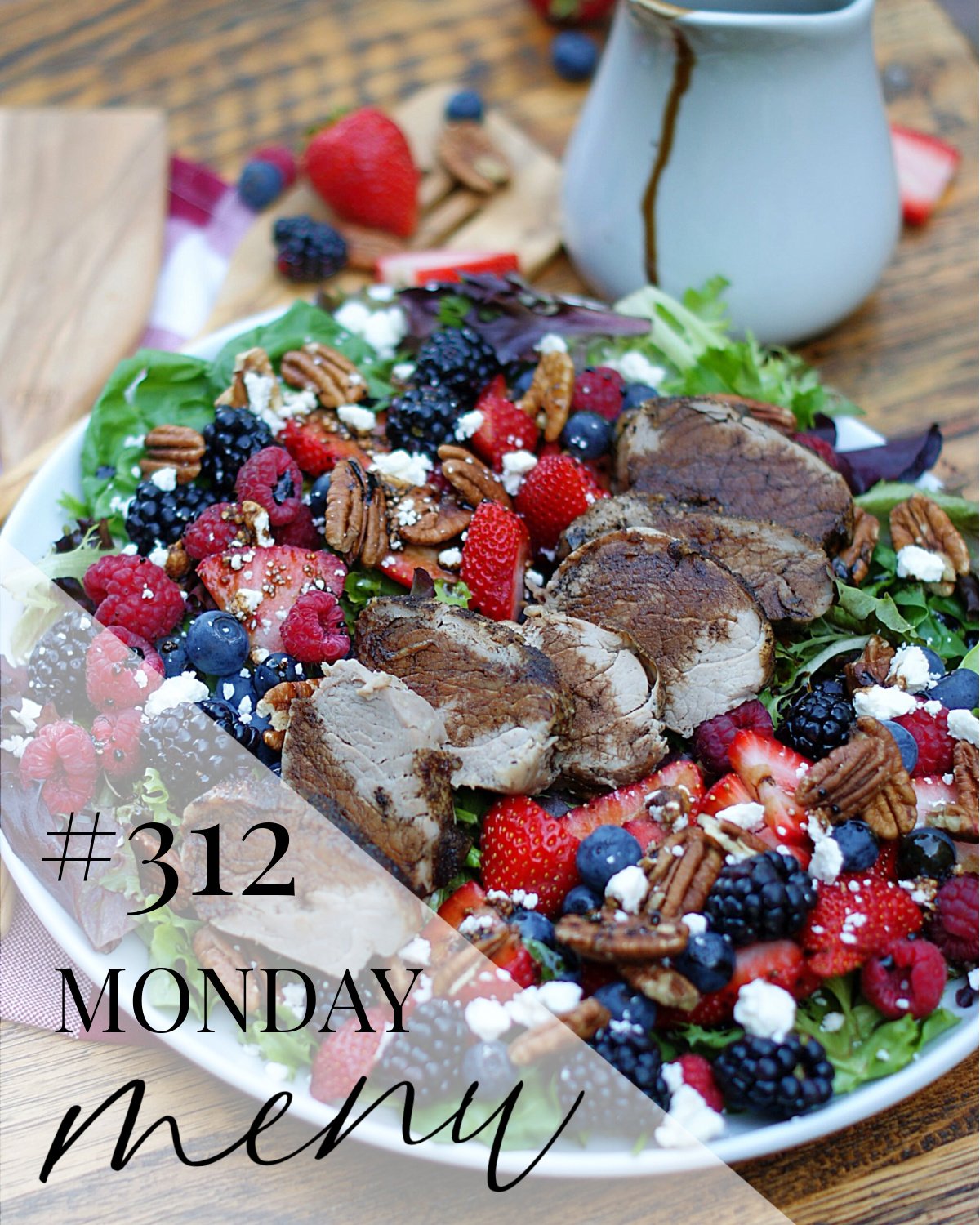 A summer berry salad on a bed of greens topped with a pork tenderloin and a cherry balsamic dressing with a Monday Menu title overlay to highlight a featured dinner recipe.
