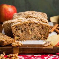 A cinnamon apple bread loaf sliced to show how it is loaded with apples, walnuts, and has sweet crispy crust.