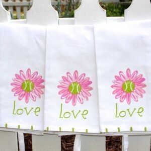 Guest towels with tennis balls in the center of pink daisies and LOVE printed underneath.
